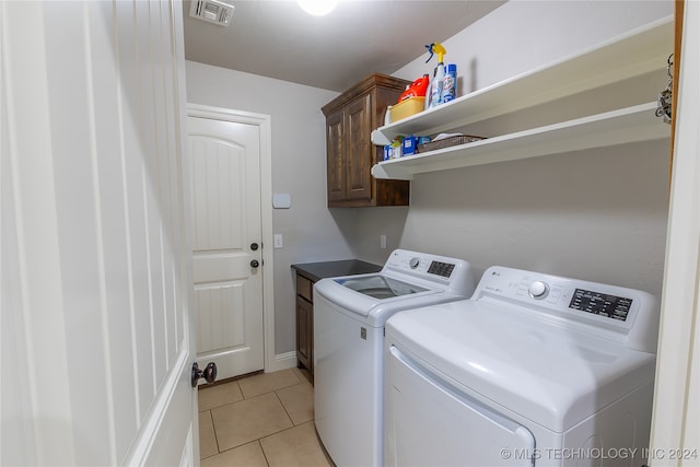 laundry room featuring cabinets, washing machine and dryer, and light tile patterned flooring