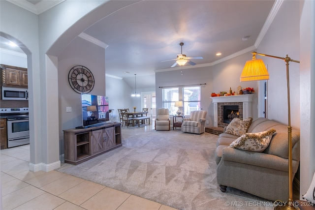 living room with a fireplace, ceiling fan, crown molding, and light colored carpet