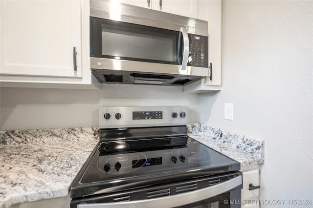 kitchen with light stone countertops, white cabinetry, and stainless steel appliances