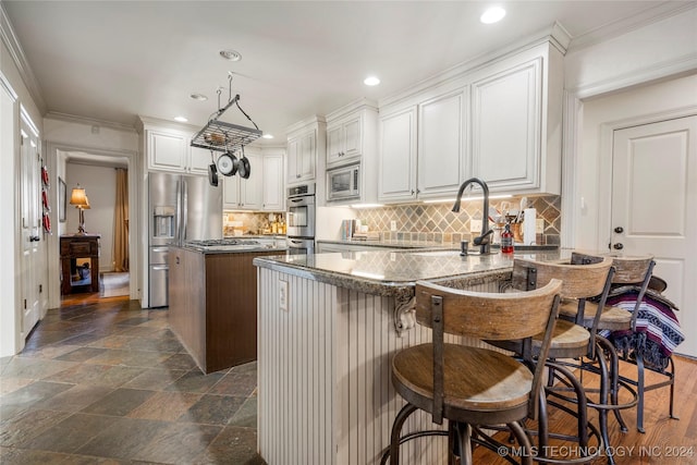 kitchen featuring white cabinetry, a center island, hanging light fixtures, dark stone countertops, and appliances with stainless steel finishes