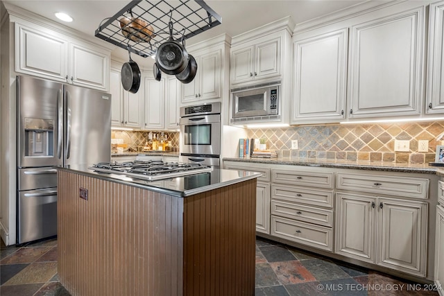 kitchen featuring light stone countertops, stainless steel appliances, a kitchen island, decorative backsplash, and white cabinets