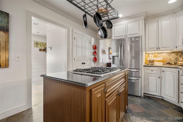 kitchen featuring white cabinets, appliances with stainless steel finishes, backsplash, and a kitchen island