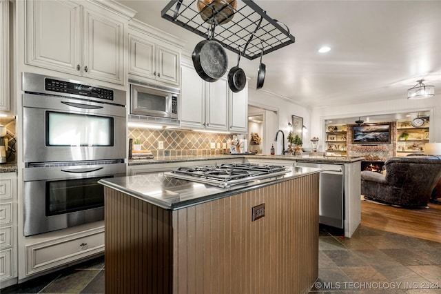 kitchen with kitchen peninsula, appliances with stainless steel finishes, a center island, and white cabinetry