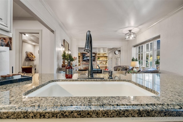 kitchen with stone countertops, ornamental molding, and sink