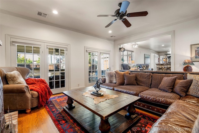 living room with wood-type flooring, a wealth of natural light, ceiling fan, and ornamental molding