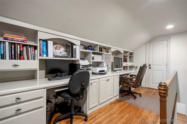 home office featuring light wood-type flooring, lofted ceiling, and built in desk