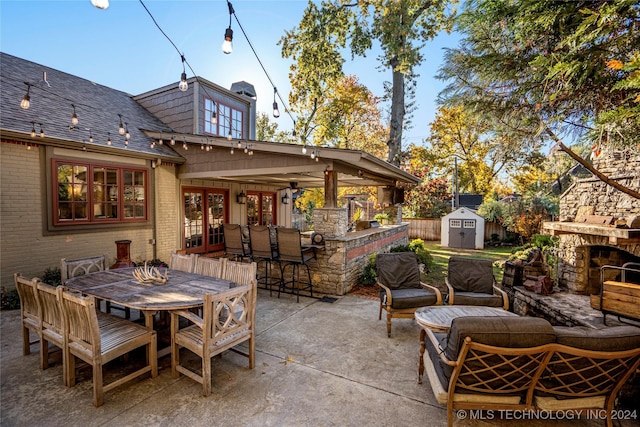 view of patio / terrace with an outdoor living space with a fireplace, a storage unit, and exterior bar