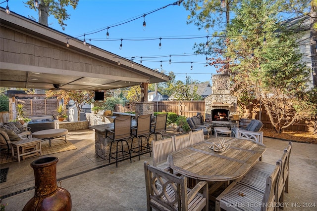 view of patio with exterior bar, an outdoor stone fireplace, a storage unit, and a grill