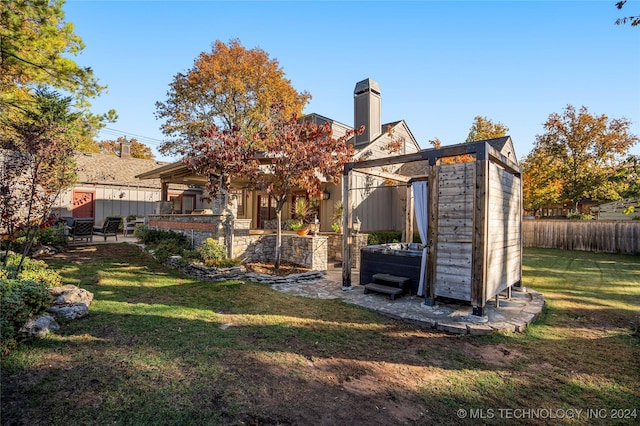 back of property featuring a lawn, a patio, and a hot tub