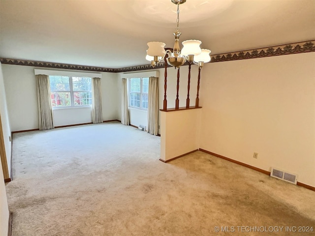 carpeted spare room with a chandelier