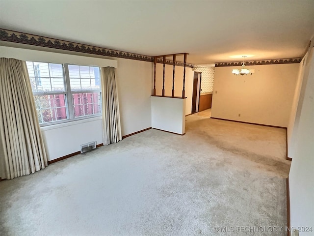 carpeted empty room featuring a chandelier