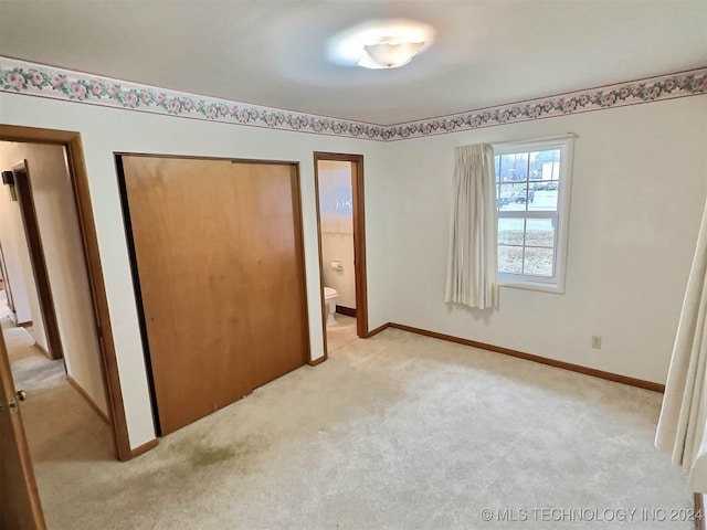 unfurnished bedroom with ensuite bath, light carpet, and a closet