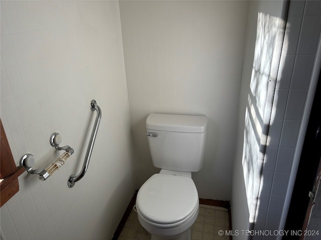 bathroom featuring toilet and tile walls