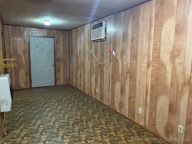 basement with an AC wall unit, dark parquet flooring, wood walls, and heating unit