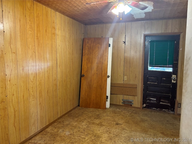 unfurnished bedroom with light colored carpet, ceiling fan, and wood walls