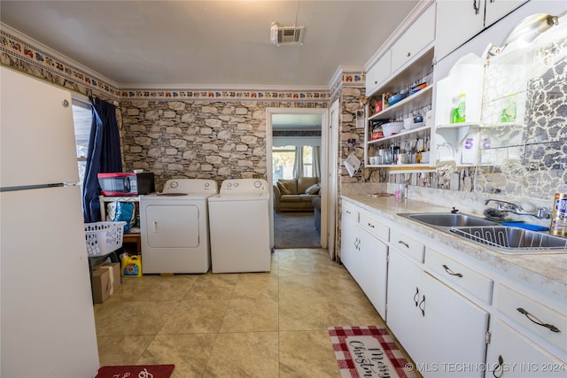 laundry area featuring washer and clothes dryer, crown molding, cabinets, and sink