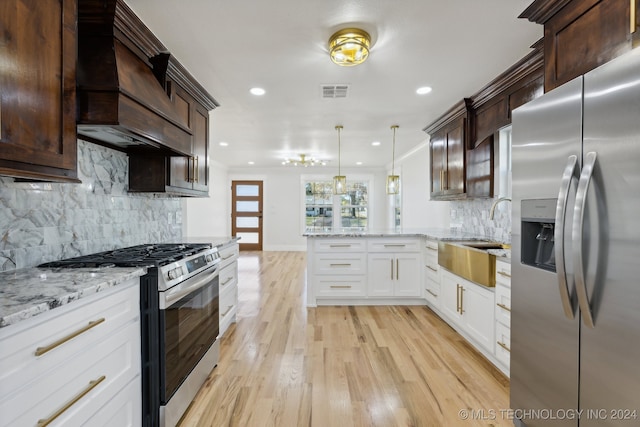 kitchen with decorative backsplash, appliances with stainless steel finishes, light hardwood / wood-style flooring, white cabinets, and hanging light fixtures