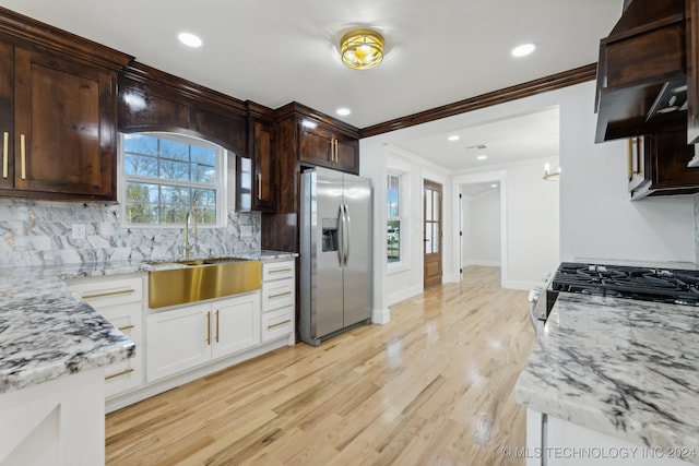 kitchen with light stone countertops, stainless steel refrigerator with ice dispenser, a wealth of natural light, sink, and light hardwood / wood-style flooring