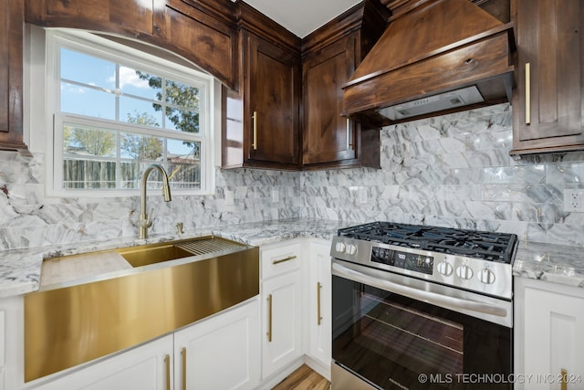 kitchen featuring gas range, decorative backsplash, light stone counters, and custom range hood