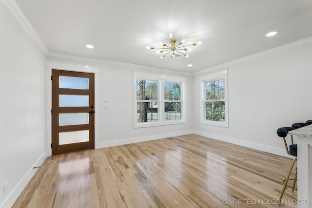 foyer entrance featuring a notable chandelier, ornamental molding, and light hardwood / wood-style flooring