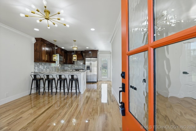 kitchen featuring kitchen peninsula, stainless steel fridge, crown molding, and light hardwood / wood-style flooring