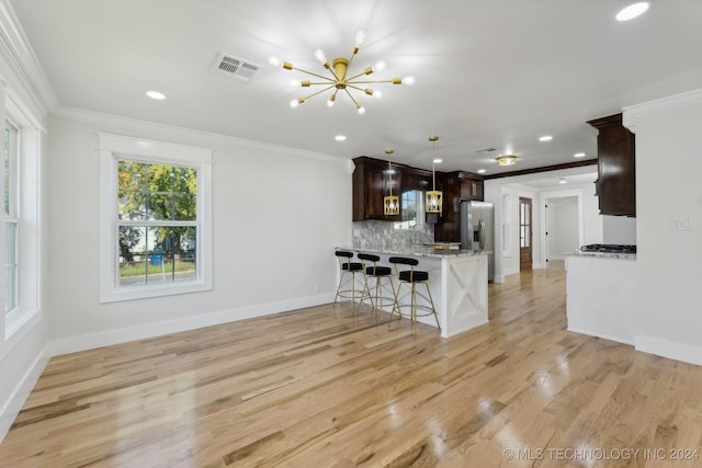 kitchen featuring light stone countertops, stainless steel fridge, tasteful backsplash, light hardwood / wood-style flooring, and hanging light fixtures