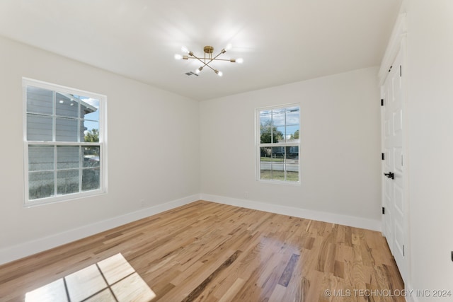 empty room featuring light hardwood / wood-style floors and a chandelier