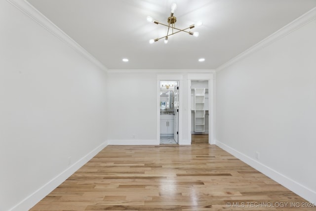 spare room featuring a chandelier, light hardwood / wood-style floors, and ornamental molding