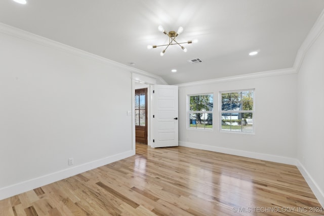 spare room featuring light wood-type flooring, crown molding, and an inviting chandelier