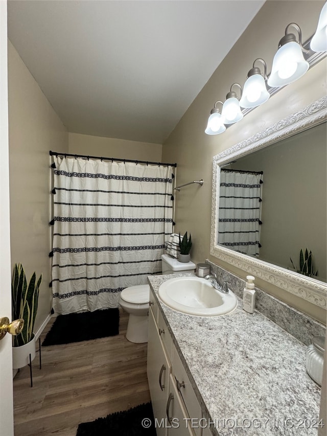 bathroom with hardwood / wood-style floors, vanity, curtained shower, and toilet