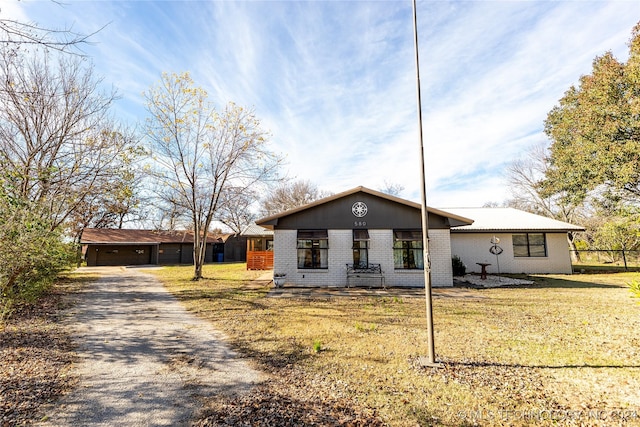 view of front facade with a garage, an outbuilding, brick siding, and a front lawn