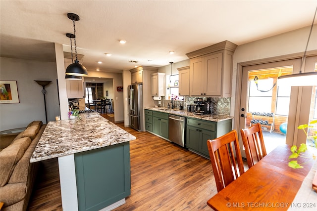 kitchen with appliances with stainless steel finishes, dark hardwood / wood-style flooring, a wealth of natural light, and pendant lighting