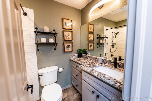 bathroom featuring a tile shower, vanity, and toilet