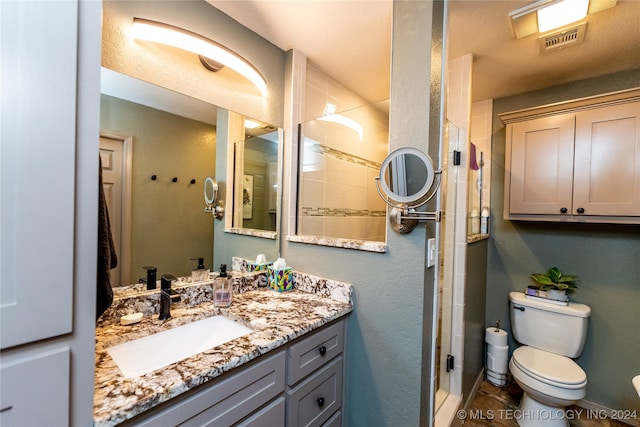 bathroom featuring toilet, vanity, and walk in shower