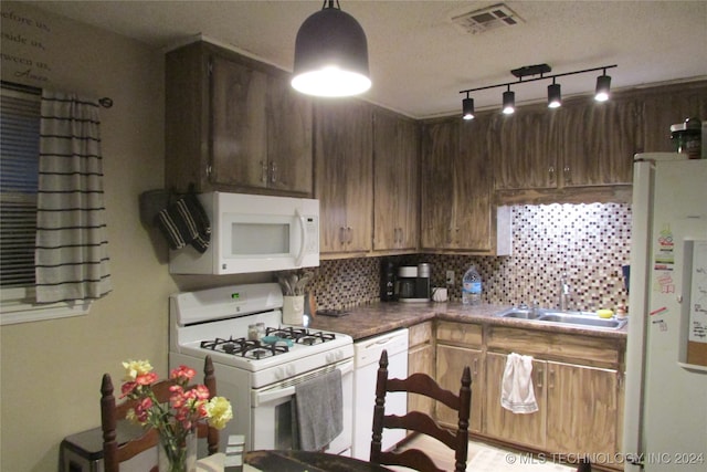 kitchen featuring a textured ceiling, white appliances, tasteful backsplash, and sink