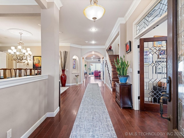 foyer with ornamental molding, an inviting chandelier, and dark hardwood / wood-style flooring
