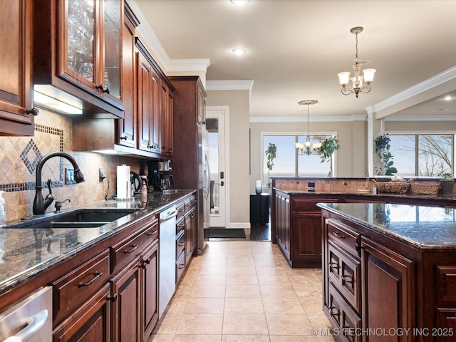 kitchen with pendant lighting, sink, dark stone countertops, ornamental molding, and an inviting chandelier