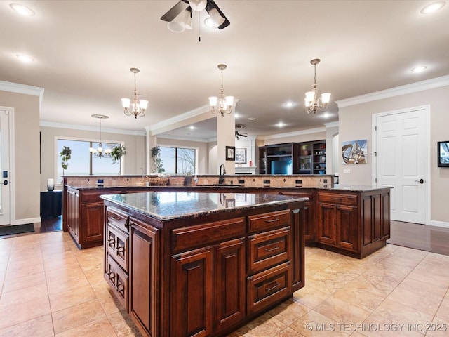 kitchen with sink, decorative light fixtures, dark brown cabinets, dark stone countertops, and a kitchen island