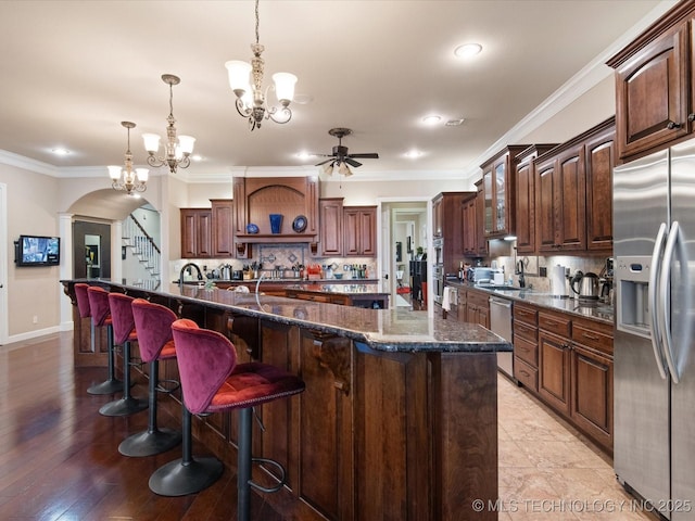 kitchen featuring pendant lighting, stainless steel appliances, a spacious island, and dark brown cabinetry