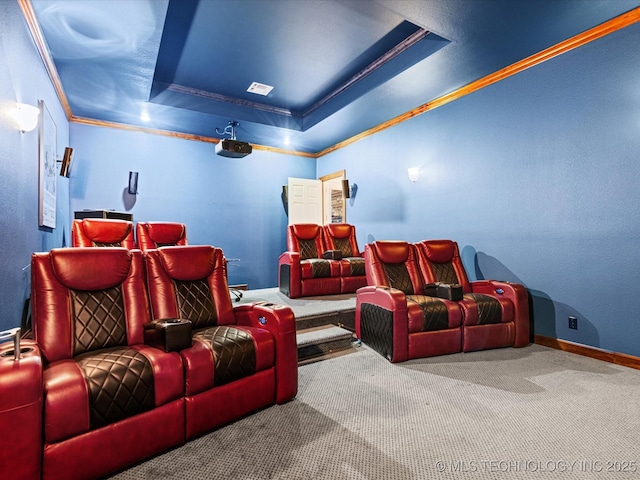 carpeted cinema room with ornamental molding and a tray ceiling