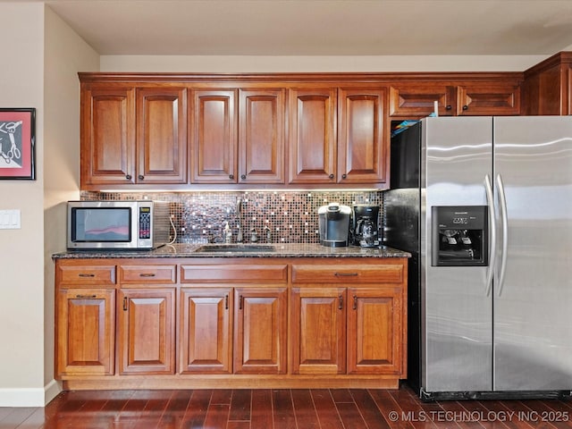 kitchen featuring stainless steel appliances, sink, backsplash, and dark stone counters