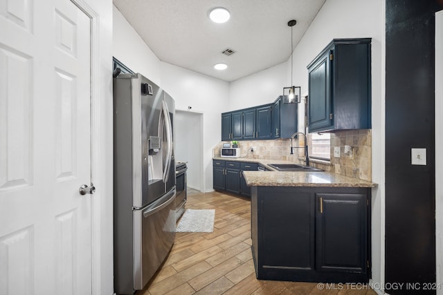 kitchen with blue cabinets, sink, light hardwood / wood-style flooring, stainless steel fridge, and tasteful backsplash