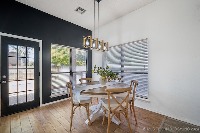 dining space featuring wood-type flooring, a textured ceiling, and a notable chandelier