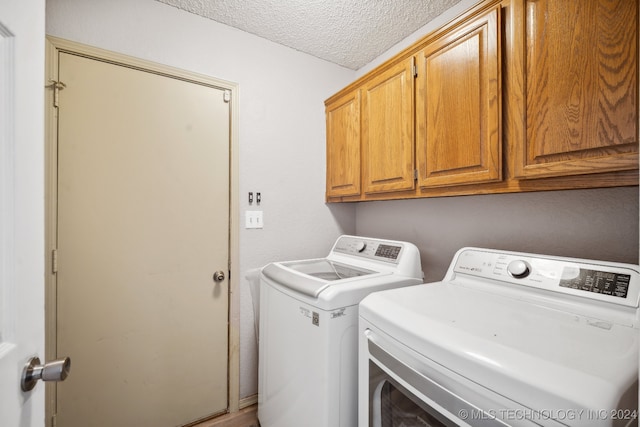 clothes washing area with cabinets, independent washer and dryer, and a textured ceiling