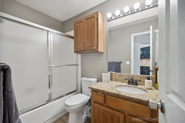 full bathroom with tile patterned floors, bath / shower combo with glass door, a textured ceiling, vanity, and toilet