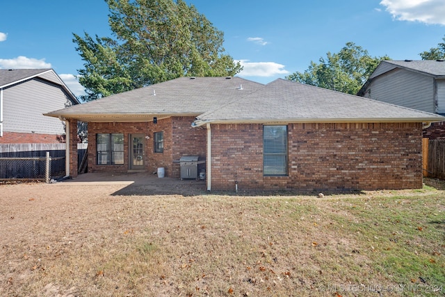 back of property with a lawn and a patio area