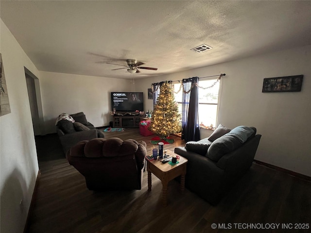 living room featuring ceiling fan, dark wood-type flooring, and a textured ceiling