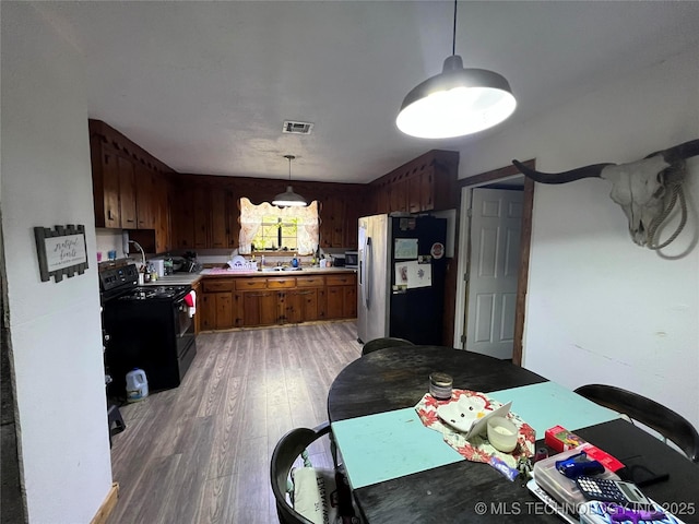 kitchen with decorative light fixtures, hardwood / wood-style flooring, electric range, and stainless steel fridge with ice dispenser