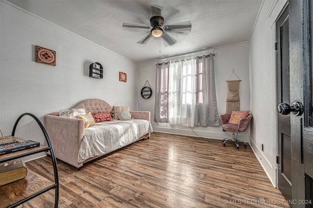 living area featuring ceiling fan, hardwood / wood-style floors, and crown molding