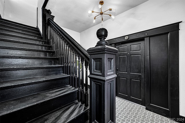 stairway featuring an inviting chandelier